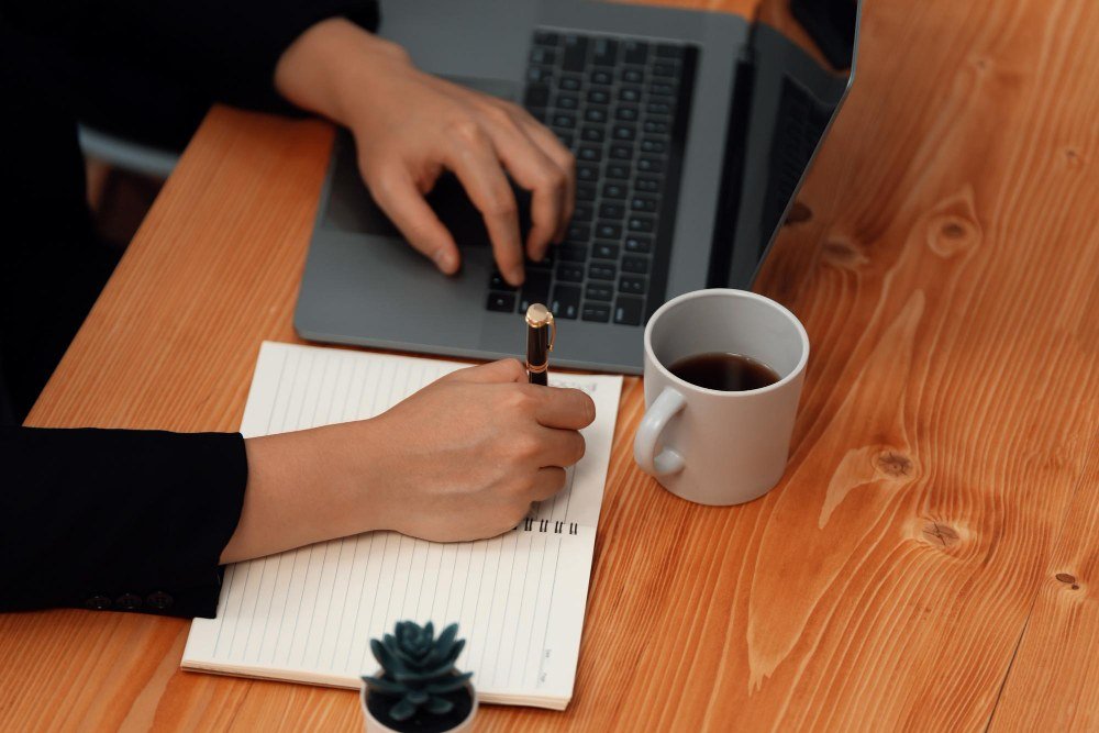 Writer researching blogs that accept guest posts on a laptop with a notebook shortlist